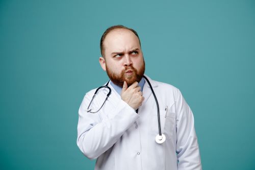 unsure-young-male-doctor-wearing-medical-coat-stethoscope-around-his-neck-keeping-hand-chin-looking-side-isolated-blue-background_141793-133498